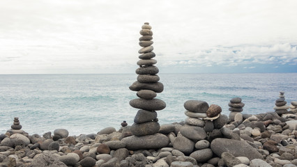 Fototapeta na wymiar Stones pyramid on pebble ocean beach symbolizing stability, zen, harmony, balance