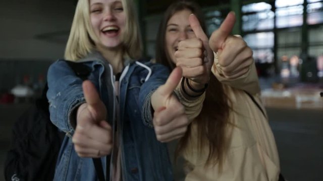 Two girls show a thumbs up