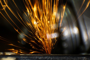 Worker cutting, grinding and polishing motorcycle metal part with sparks indoor workshop. Super...