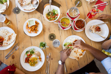 leisure, food and people concept - group of happy african american friends eating at restaurant table