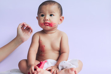 asian cute baby girl eating red dragon fruit. newborn baby on white background