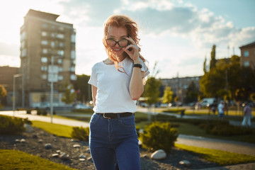 Portraits of a charming red-haired girl with a cute face. Girl posing for the camera in the city...