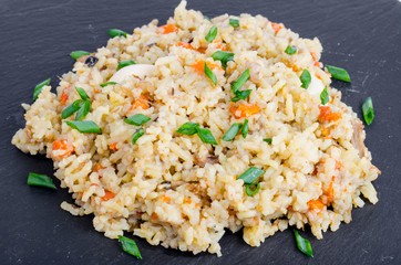 Bunch delicious golden pilaf on black stone