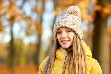 childhood, season and people concept - portrait of happy girl at autumn park