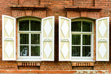 two windows with the wooden carved architrave in the old wooden house in the old Russian town.