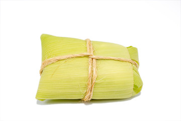 Brazilian pamonha on white background, typical dessert of the rural cities of Brazil. Sweet corn with cheese served in the straw. Rural sweets made in the states of Minas Gerais and Goiais.