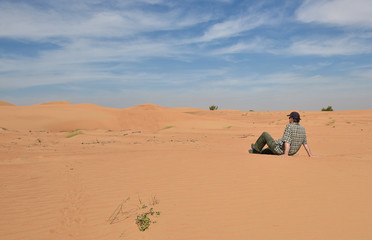 Mann sitzt in der Sandwüste