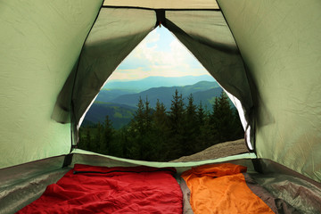 Camping tent with sleeping bags in mountains, view from inside