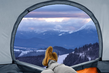 Closeup of man in camping tent on snowy mountain hill, view from inside