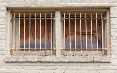 Security bars mounted on brick building with plywood windows.