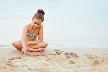 Adorable little girl building a sandcastlle at the seashore
