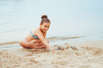 Adorable little girl building a sandcastlle at the seashore