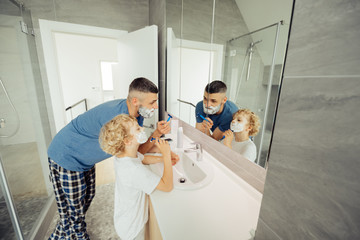 Pleasant nice man teaching his son to shave