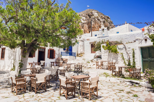 Traditional greek street with flowers and cafe tables in Amorgos island, Cyclades, Greece