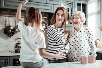 Emotional child sitting on the table and telling interesting story to relatives