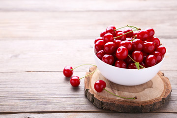 Fresh red cherry fruit in plate on grey wooden table