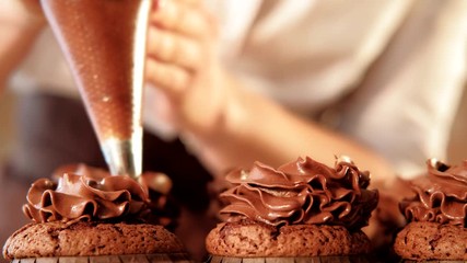 Whip piping skills. Confectioner decorating chocolate cupcakes