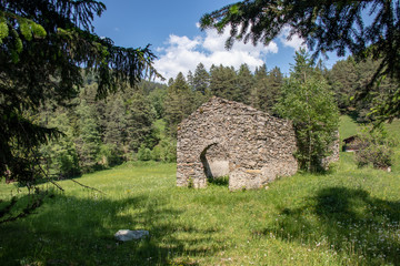 Fototapeta na wymiar View of a meadow with dilapidated stone hut at blue sky in the swiss alps