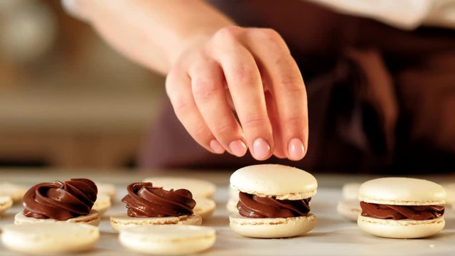 Pastry cooking. Sweet dessert. Vanilla macarons with chocolate filling assembling