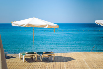resort hotel idyllic peaceful place of wooden deck waterfront Red sea beach with white loungers and umbrella from bright summer sun, vacation wallpaper pattern picture with empty space for copy  