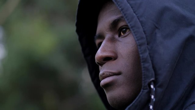 Thoughtful confident hooded young black african migrant-outdoor