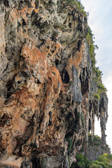 Big textured natural limestone cliffs with stone icicles formations on Phra Nang beach on Railay in...