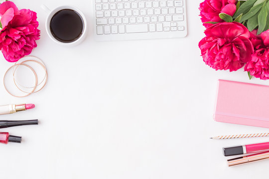 Flat lay blogger or freelancer workspace with a notebook, keyboard, red peonies on a white background