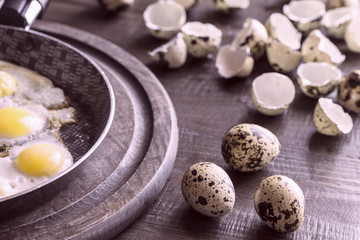 Fototapeta na wymiar fried quail eggs in a frying pan, raw quail eggs and shell from on the table. cooking eggs from quail eggs.