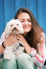 young brunette woman sitting outdoors with her little dog