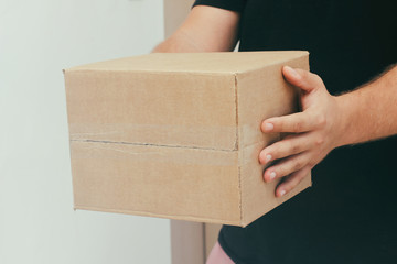 Delivery man with cardboard parcel. Hand holding the delivery box.