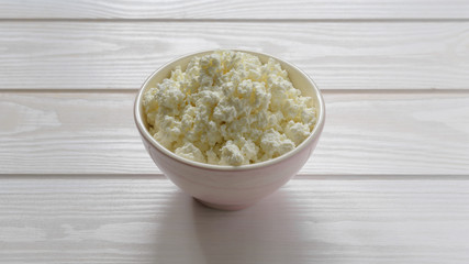 cottage cheese in a pink bowl on a light wooden table