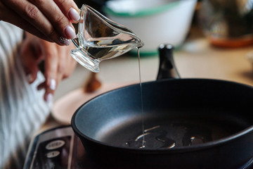 Vegetable oil pouring from a bottle into a frying pan.