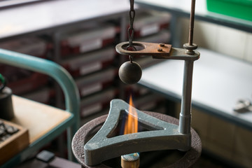 Gravesande experiment: iron ball is heated by a hot flame and will not fit in the ring above after heating. Physics experiment showing the principle of expansion.