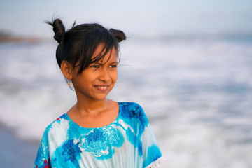  beach lifestyle portrait of young beautiful and happy Asian child girl 8 or 9 years old with cute double buns hair style playing carefree in the sea enjoying holiday