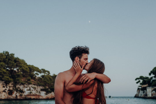 man and woman kissing near body of water