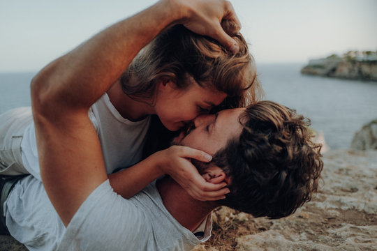 man and woman kissing near sea