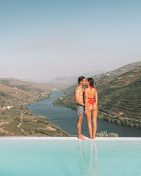 man and woman kissing on the edge of infinity pool during daytime