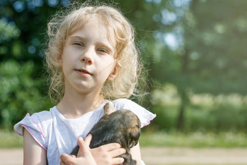 the girl is holding a very small puppy. daylight. close-up.