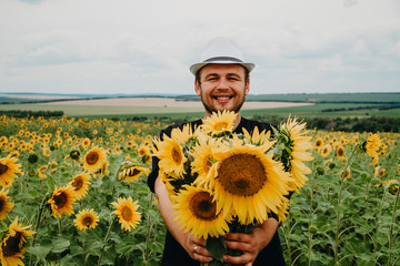 A man gives flowers, smiles, stands in a field.