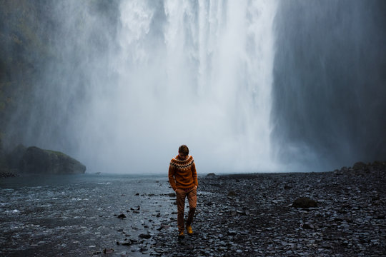 selective focus photography of person standing near waterfalls