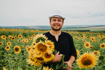 Portrait of a male beekeeper close-up in a field of sunflowers, the beekeeper smiles and looks into...