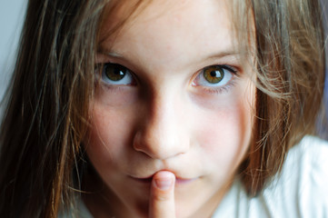 Naklejka premium Beautiful young girl with long hair puts a finger in her mouth, close portrait