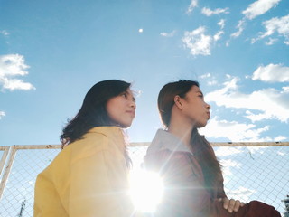 two girl standing in front of cyclone fence during daytime