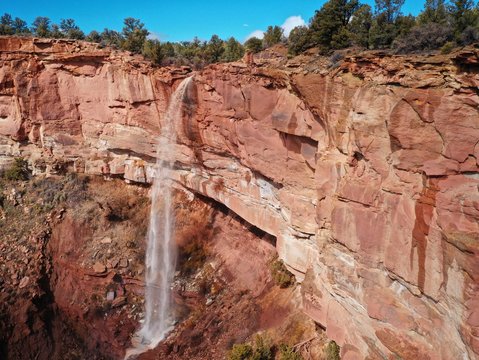 Waterfall flowing off red stone mountain cliff