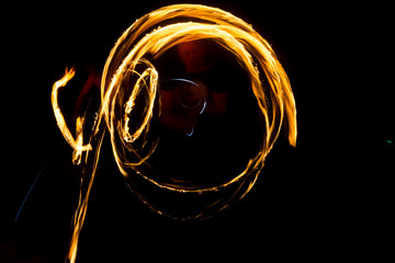 The artist shows a fire show at night spinning torches, circles of fire and loops