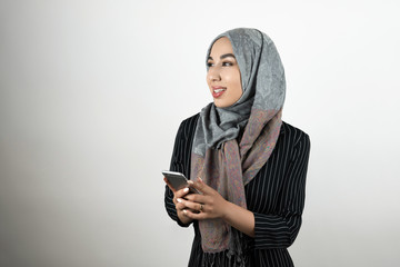 young beautiful Muslim woman wearing turban hijab headscarf holding smartphone in her hands isolated white background