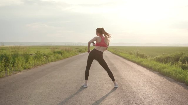 At sunset shot back young woman in headphones dancing to camera having fun in road field athletic countryside exercise female fit fitness fly forest girl healthy jogger marathon workout slow motion