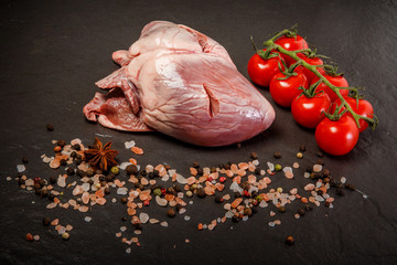 large pork raw heart served with spices and tomatoes