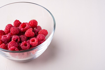 Raspberry red berries in transparent glass bowl plate tasty sweet bright on white background copy space macro