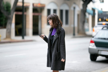 Young female using mobile phone app and waiting for a rideshare or pedestrian tourist checking...